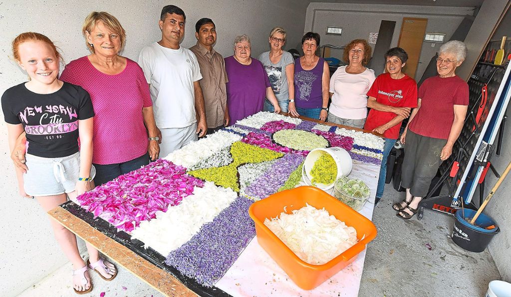 Frauen aus der Gemeinde und Flüchtlinge halfen mit bei der Gestaltung von Blumenteppichen. Fotos: Maier