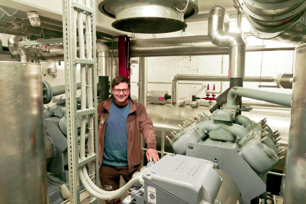 Der Technische Leiter der KEB, Hermann Vikoler,  steht im Raum der Kühlanlage  neben einem der Verdichter, dahinter ist der Ammoniak-Tank zu sehen.