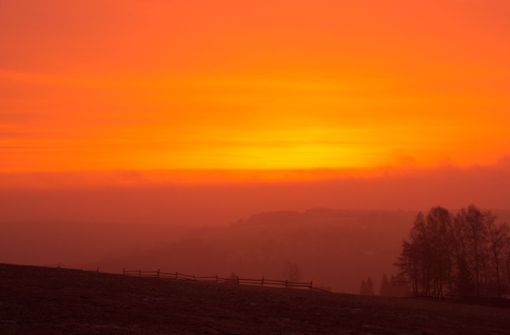 Wegen des Saharastaub in der Luft ist der Himmel bei Sonnenaufgang rötlich gefärbt –  wie hier im sächsischen  Bärenstein. Foto: Foto: promovie/dpa/Oliver Kaufmann