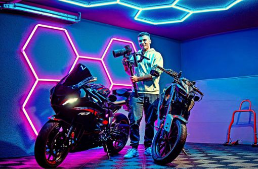 Erick Bensel steht stolz mit einem Teil seines Kameraequipments zwischen seinen beiden Motorrädern in seiner Garage. Foto: Baur