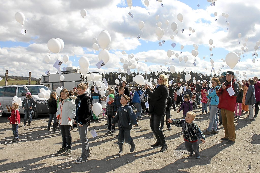 Zum Gedenken an die verstorbenen Tiere lassen Kinder wie Erwachsene Hunderte weiße Luftballons neben der Ruine des Stalls aufsteigen.