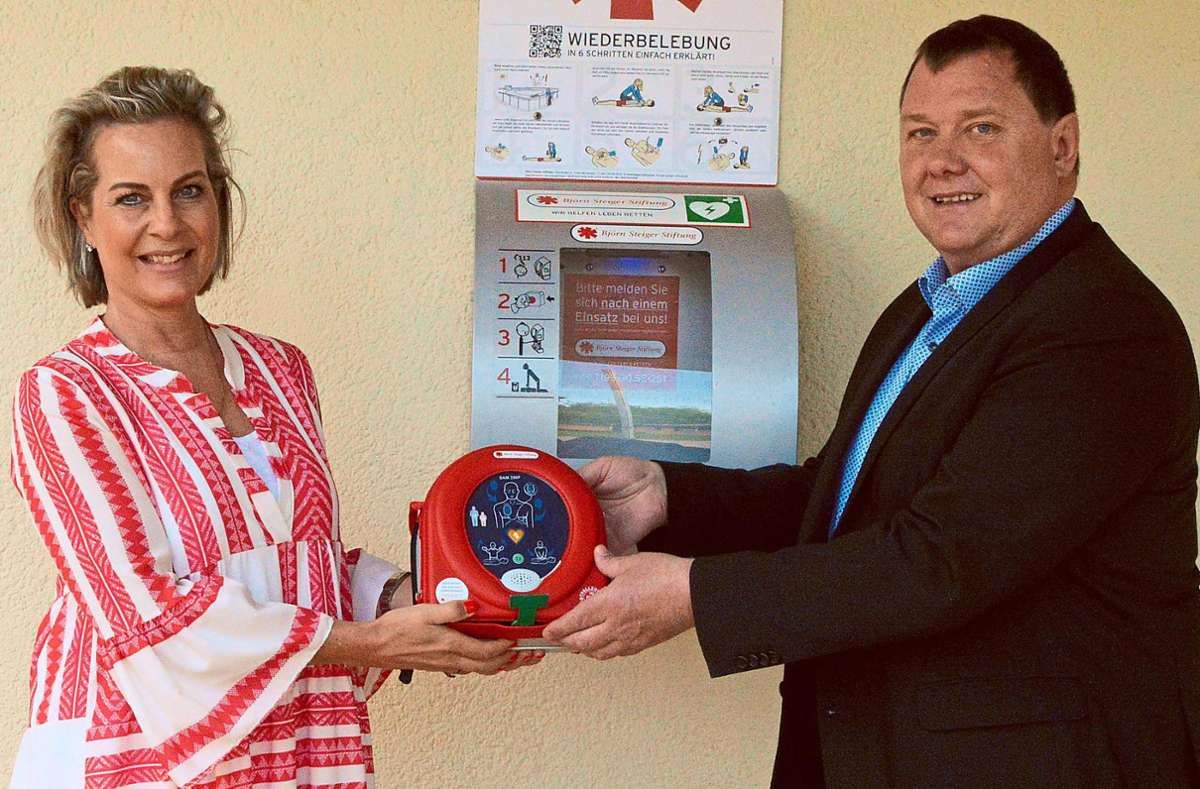 Projektleiterin Gabriele Ballmer übergibt Bürgermeister Michael Lehrer den gespendeten Laien-Defibrillator. Foto: Herzog