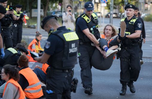 Aktivisten der Klimaschutzgruppe Letzte Generation werden während einer Straßenblockade auf dem Mehringdamm in Berlin von Polizeibeamten weggetragen. Foto: dpa/Sebastian Gollnow