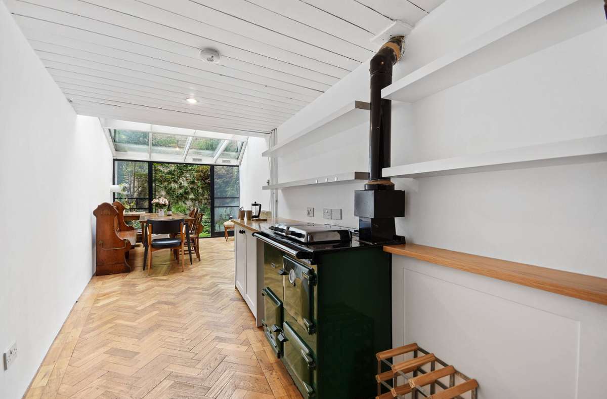 Im Untergeschoss des Hauses findet sich neben einer kleinen Küchenzeile ein Esstisch sowie Glastüren, die zum Garten führen.