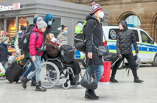 Geflüchtete aus der Ukraine gehen mit ihrem Gepäck und einer Seniorin im Rollstuhl über den Leipziger Hauptbahnhof. Hier werden sie von ehrenamtlichen Helfern empfangen und betreut. Foto: Woitas