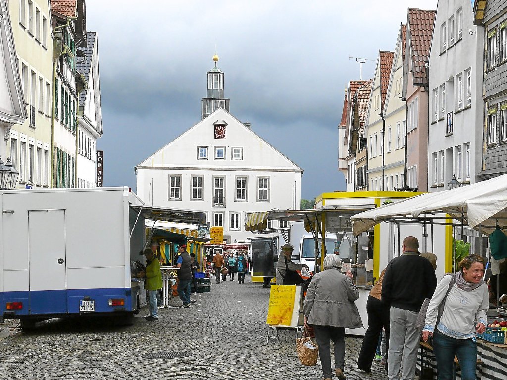 Eine dunkle Wolkenwand hängt über dem Hechinger Marktplatz. Nur wenige Menschen kaufen aufgrund des Regenwetters auf dem Wochenmarkt ein.