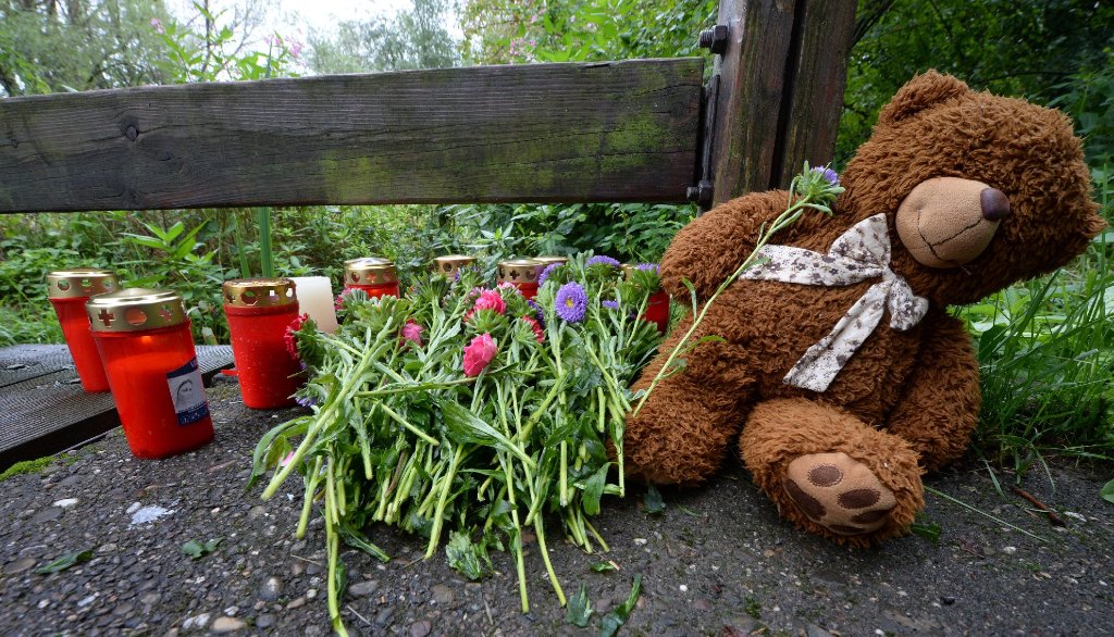 Ein Teddybär, Grablichter und Blumen liegen in Freiburg am Fundort des getöten achtjährigen Jungen.