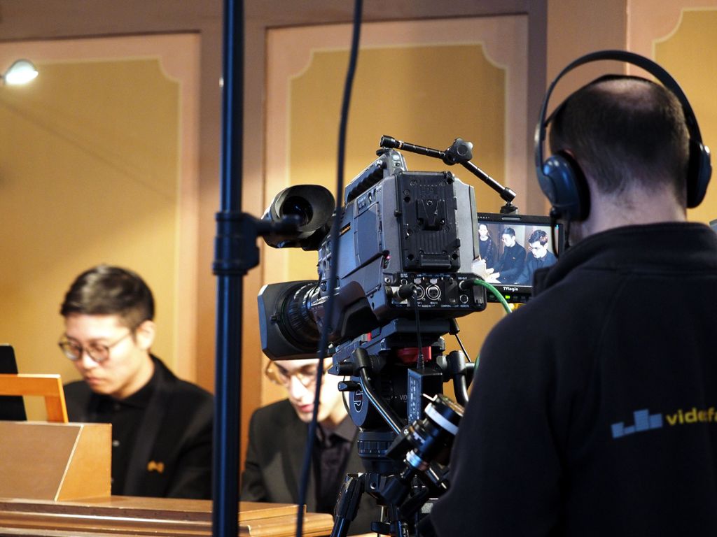 Das virtuose Spiel der Wettbewerbsteilnehmer auf den Orgeln wird für die Zuhörer per Kameraübertragung  auf einer Leinwand im Altarraum sichtbar gemacht.