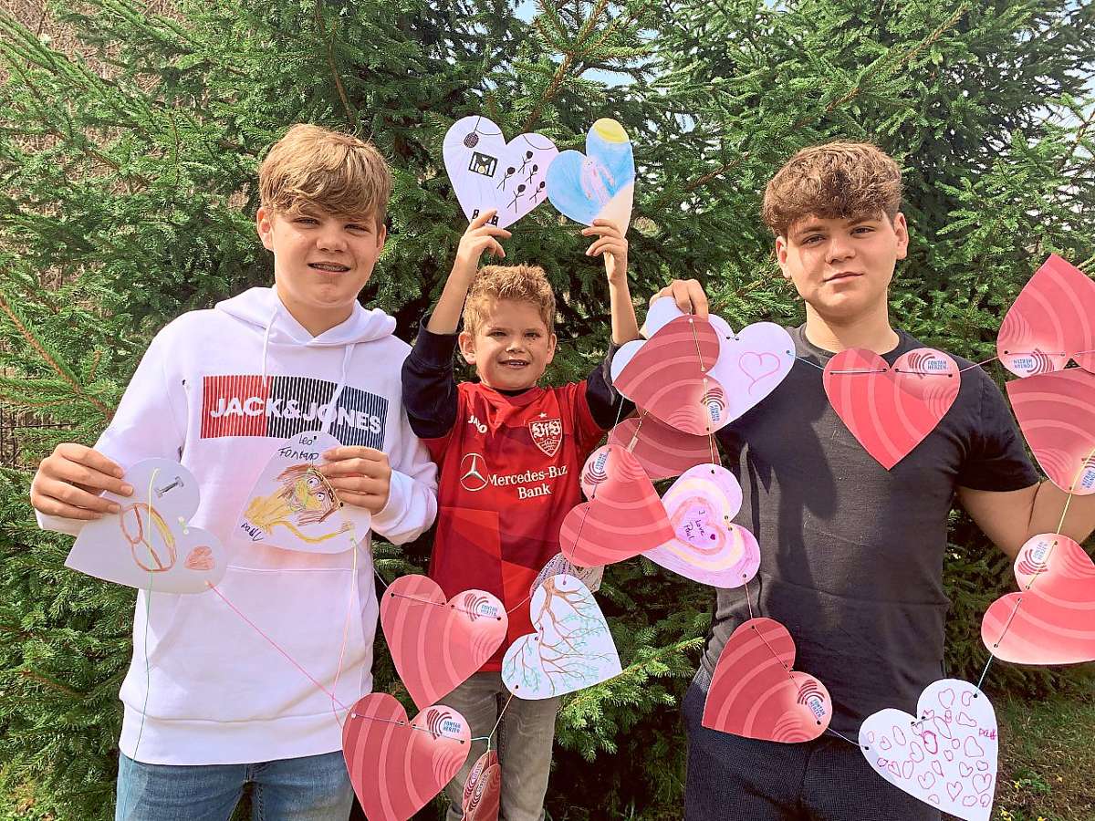 Mit tatkräftiger Unterstützung der Familie wächst die Herz-Kette von Tag zu Tag (von links): Pauls Bruder Levin, Paul und sein Bruder Lucas. Foto: Merkel