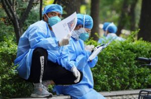 Mitarbeiter des Gesundheitswesens in Schutzkleidung. PCR-Massentests sind in China nach wie vor an der Tagesordnung. Foto: dpa/Andy Wong