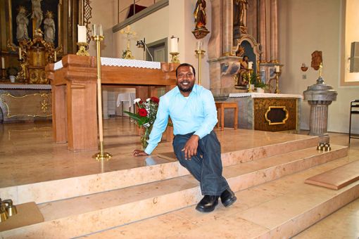 Pfarrer Shibu Vincent Pushpam sitzt auf den Stufen vor dem Altar der Ratshausener St.-Afra-Kirche. Der indische Priester fühlt sich im Oberen Schlichemtal wohl.  Foto: Visel Foto: Schwarzwälder Bote