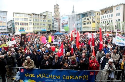Teilnehmer einer Mai-Kundgebung des Deutschen Gewerkschaftsbundes (DGB) stehen in Stuttgart auf dem Marktplatz vor einem Banner mit der Aufschrift Wir machen Europa. Foto: dpa