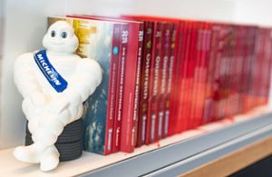 Ein Michelin-Männchen steht neben Guide Michelins verschiedener Jahrgänge. Foto: Frank Rumpenhorst/dpa