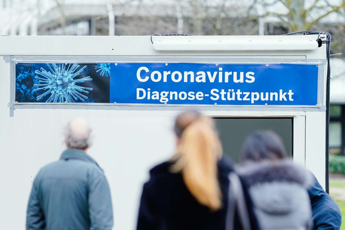 Menschen stehen auf dem Gelände eines Universitätsklinikums vor speziell für den Test auf den neuartigen Coronavirus aufgestellten Containern, an deren Eingang ein Transparent mit der Aufschrift Coronavirus Diagnose-Stützpunkt angebracht ist. Foto: (dpa)