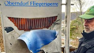 Wolfgang Burger zeigt Teile der von Vandalen herausgerissenen Platte mit der Beschreibung der Fliegersperre. Die Stahlplatte darunter ist stark nach hinten ausgebeult. Foto: Häring