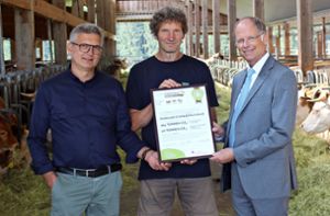Wolfgang Abler (Geschäftsführer CarboCert, links) überreicht Arendt Gruben das Zertifikat für die CO2-Kompensation durch den Humusaufbau von Landwirt Christoph Trütken. Foto: Sparkasse/Michael Pohl