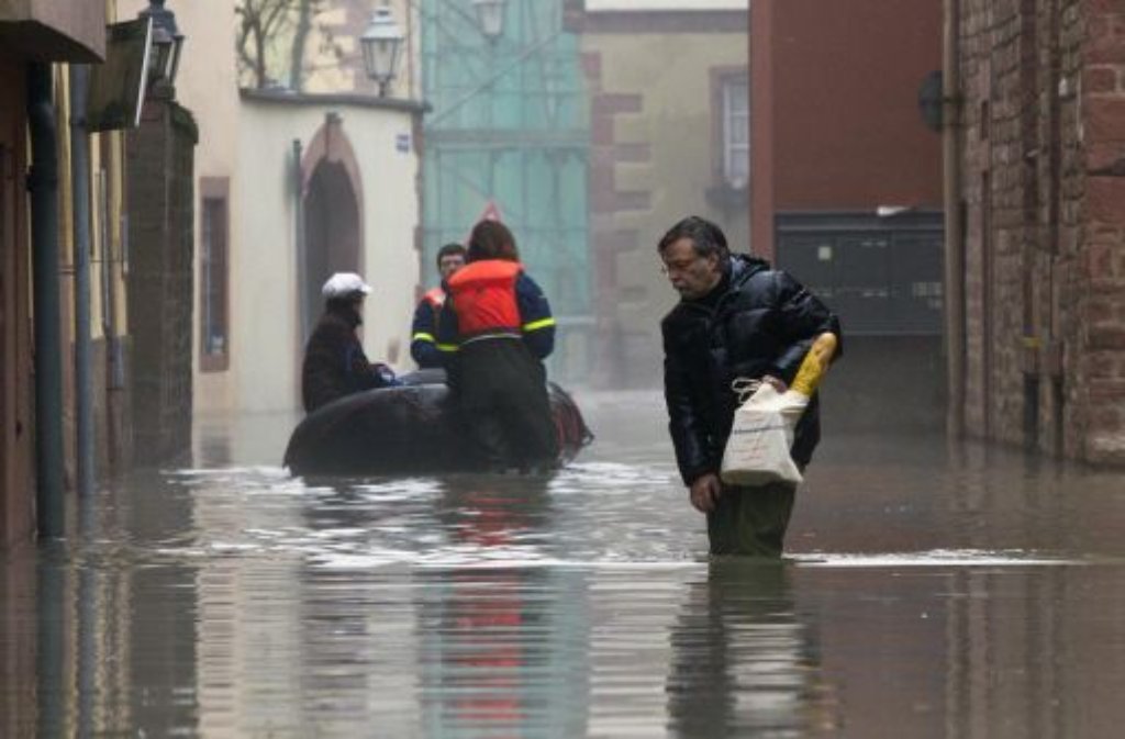Ein Mann watet am Montagmorgen mit seinen Einkäufen durch eine überflutete Gasse in der Innenstadt.