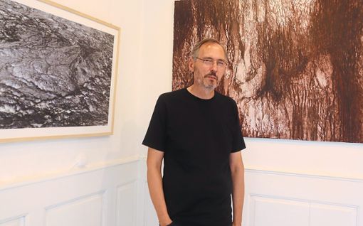Johannes Traub vor zwei großformatigen Fotos, bei denen  er die Farben umgekehrt hat.  Foto: Haberer