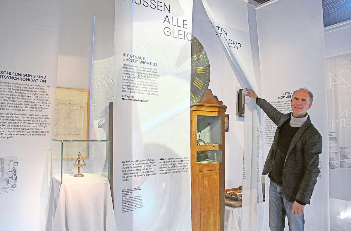 Museumsleiter Michael Hütt zeigt bei der neuen Sonderausstellung das Prinzip der Info-Banner aus Tüchern, die zurück geschoben werden können und interessante Objekte, wie hier die Schwenninger Rathaus-Uhr von 1860, hervorbringen.