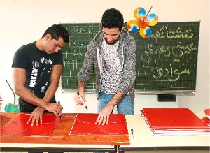 Adeel Hmad (links) aus Pakistan und Anas Alzokane aus Syrien schneiden Blumen aus Kunststoffplatten. Mit diesen wird für die Gartenschau 2017 geworben. Foto: Glaser Foto: Schwarzwälder-Bote