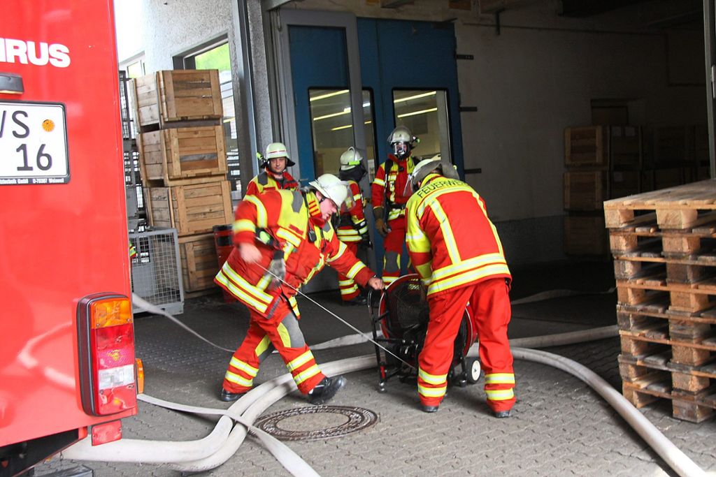 Nach dem Einsatz mit Atemschutz unter der Leitung von Kommandant Dirk Schuler (hinten links) wird mit Belüftern das Firmengebäude vom Rauch befreit.