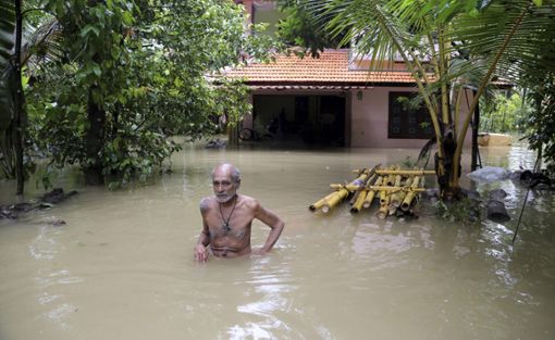 Das Haus steht unter Wasser, ein verzweifelter Mann geht durch die Fluten, um ein Rettungsboot zu erreichen. Der südindische Bundesstaat Kerala ist vom verheerendsten Monsun der vergangenen 100 Jahre getroffen worden. Foto: Rahi Foto: Schwarzwälder Bote