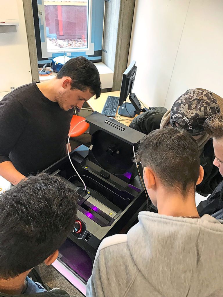 Lehrer Ralph Klein und Schüler des Profilfaches  Naturwissenschaft und Technik   beäugen den Druckfortschritt an einem der schuleigenen 3D-Drucker Foto: Schule