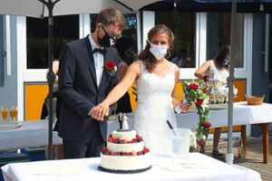 Auch beim Anschneiden der Hochzeitstorte fehlte der für das Brautpaar eigens individuell angefertigte Mundschutz nicht.  Foto: Göttling