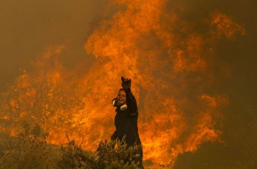 Ein Feuerwehrmann steht vor dem Flammenmeer in einem Athener Vorort. Foto: Imago/Xinhua/Marios Lolos