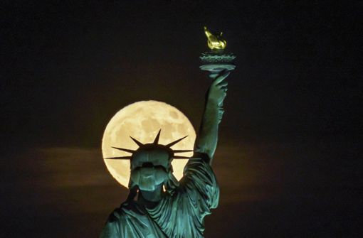 Der Supermond  geht hinter der Freiheitsstatue in New York auf. Weitere Impressionen des Vollmondes finden Sie in unserer Galerie. Foto: dpa/J. David Ake