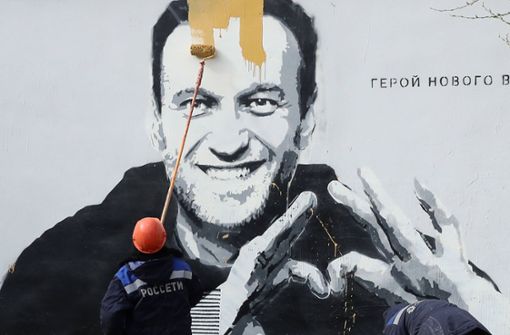 Ein Mitarbeiter des russischen Stromanbieters Rosseti entfernt ein Gemälde an einem Trafohäuschen in Sankt Petersburg, das den Oppositionellen Alexej Nawalny zeigt. Foto: imago images/Alexander Demianchuk