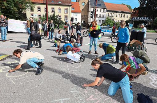 Mit Kreide schreiben die Jugendlichen ihre Forderungen auf den Platz vor dem Riettor. Foto: Heinig