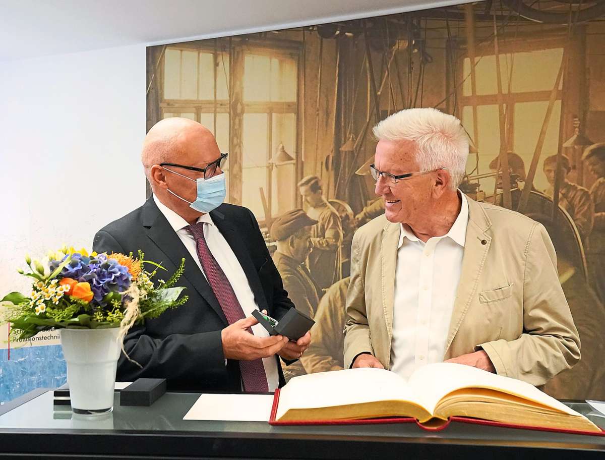 Bürgermeister Michael Rieger überreicht Ministerpräsident Winfried Kretschmann einen Stift, mit dem er sich in das Goldene Buch der Stadt einträgt.