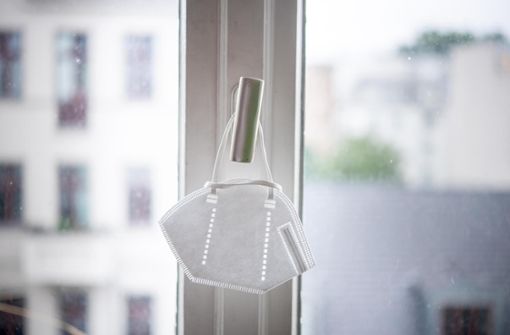 Eine FFP2-Maske hängt an einem Fenster-Griff – die Schutzmasken haben die meisten Menschen derzeit stets griffbereit. Foto: Scheurer