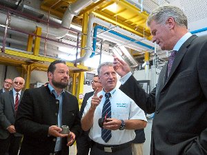 Minister Alexander Bonde (von links) lässt sich von Mahle-Mitarbeiter Matthias Seifried und dem Europa-Technologie-Chef Georg Dietz die Kolbenproduktion erklären. Foto: Schulz