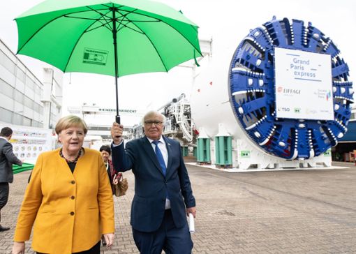 Ungewöhnlicher Anblick: Tunnelbau-Pionier Martin Herrenknecht, bekannt als einer der schärfsten Kritiker von Angela Merkel, hält der Kanzlerin den Schirm.   Foto: Patrick Seeger