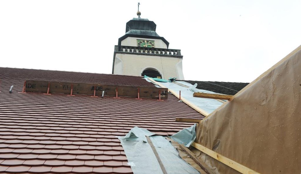 Die Dachsanierungsarbeiten schreiten zügig voran. Während das westliche Kirchendach bereits mit neuen roten Biberschwanzziegeln eingedeckt ist, liegen auf der östlichen Dachhälfte noch die alten Ziegel.