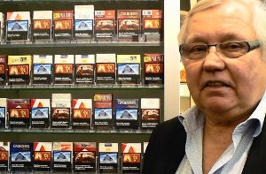 Tabakwarenhändler Günther Held steht in seinem Laden in Weilimdorf vor einem Regal voller Zigarettenschachteln – darauf sind Schockbilder zu sehen, mit denen die Politik Raucher abschrecken will Foto: StN