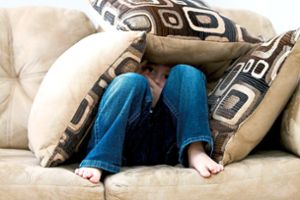 Ein Kind versteckt sich auf einem Sofa inmitten von Kissen. Die Zahl der psychisch erkrankten Jungen und Mädchen in der Region steigt laut AOK  immer mehr an. Foto: AOK