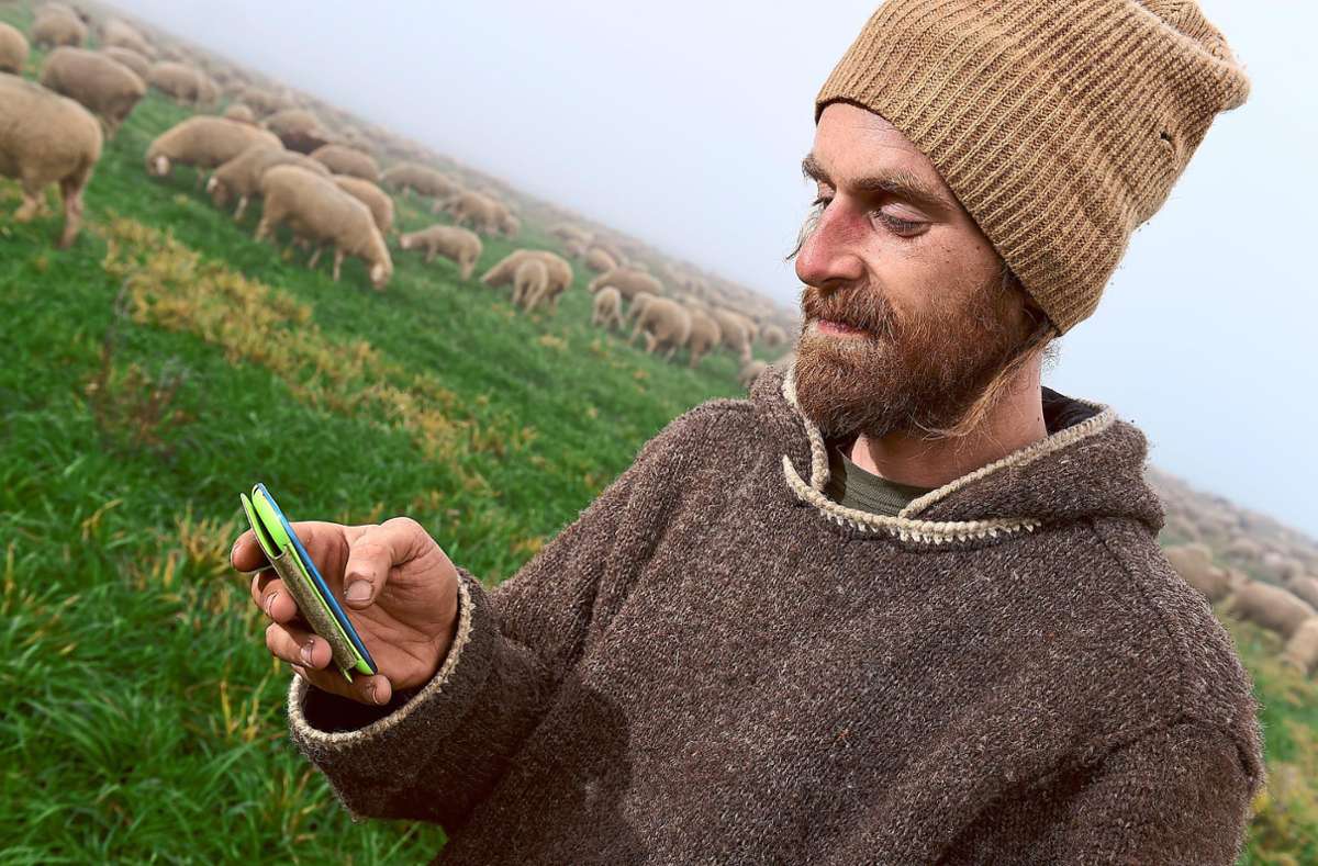 Ein Schäfer schreibt auf seinem Handy eine Textnachricht. Auch auf dem Land schreitet die Digitalisierung voran.