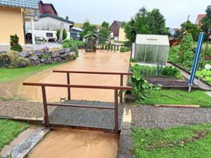 Der anhaltende Regen lässt den Pegel des Kompromißbachs in Kommingen so stark ansteigen, dass dieser anliegende Gärten überflutet. Foto:  Lutz