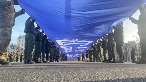 Ein riesige blaue Fahne mit der Aufschrift Latvija Nato 20 wird vor dem Freiheitsdenkmal entrollt. Lettland feiert 20 Jahre Nato-Mitgliedschaft. Foto: Alexander Welscher/dpa